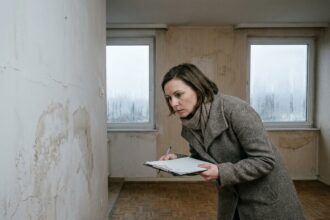 Femme inspectant des défauts d'humidité sur un mur lors d'une visite de logement en hiver